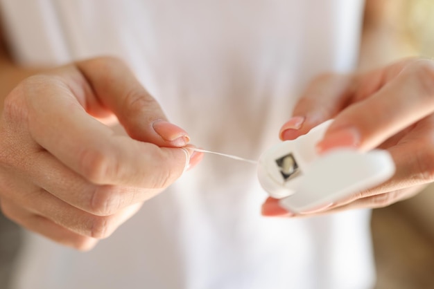 Gros plan sur des mains féminines tenant un fil de nettoyage des dents ou un fil dentaire soins dentaires et