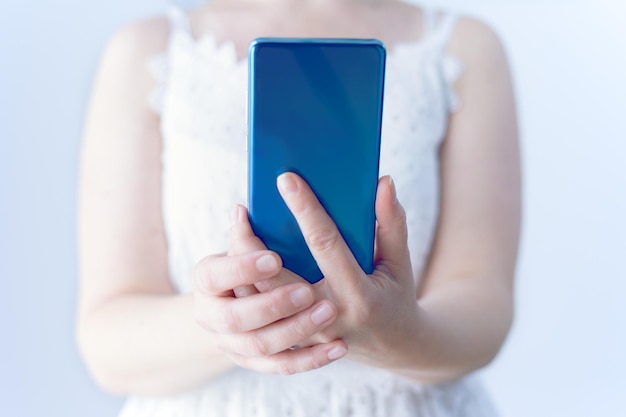 Gros plan des mains féminines tenant un téléphone portable à l'aide de la technologie