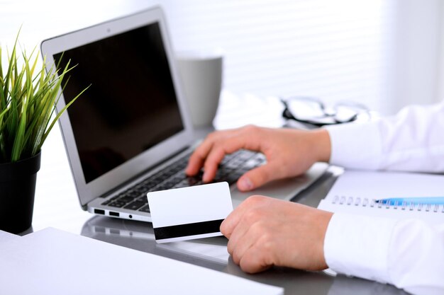 Gros plan des mains de femme d'affaires à l'aide d'une carte de crédit et d'un ordinateur portable