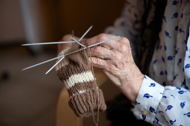Gros plan des mains d'une femme âgée chaussette à tricoter