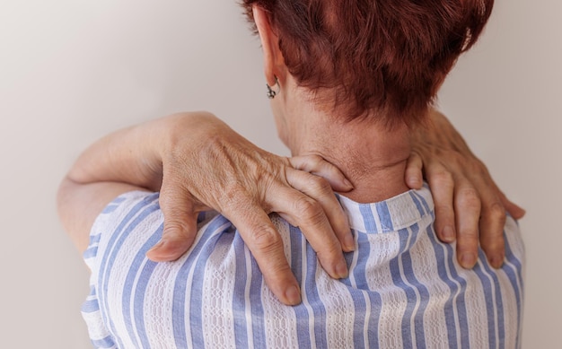 Photo gros plan sur les mains d'une femme âgée massant son propre cou maladies neurologiques de la colonne vertébrale