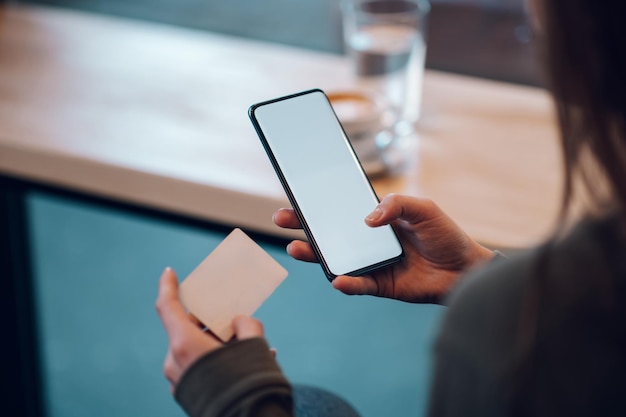 Gros plan sur les mains d'une femme à l'aide d'un smartphone et d'une carte de crédit