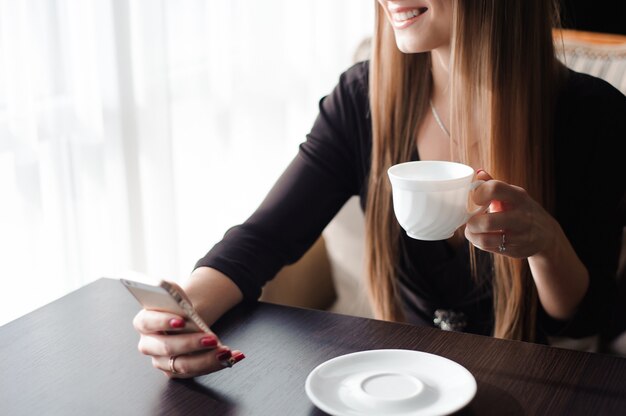 Gros plan des mains femme à l'aide de son téléphone portable au restaurant, café.