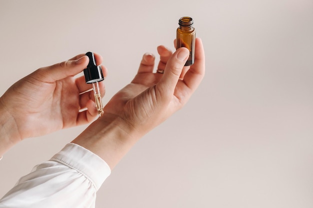 Gros plan sur les mains d'une femme appliquant de l'huile essentielle sur son poignet à l'intérieur