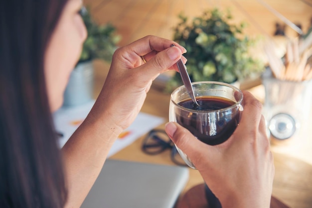 Gros plan des mains d'une femme assise au bureau tenant une tasse de café sucrée se détendre et profiter avec plaisir tasse de café chaud à la main