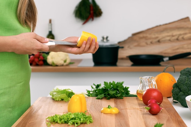 Gros plan sur les mains d'une femme cuisinant dans la cuisine. Femme au foyer coupant une salade fraîche. Concept de cuisine végétarienne et saine.