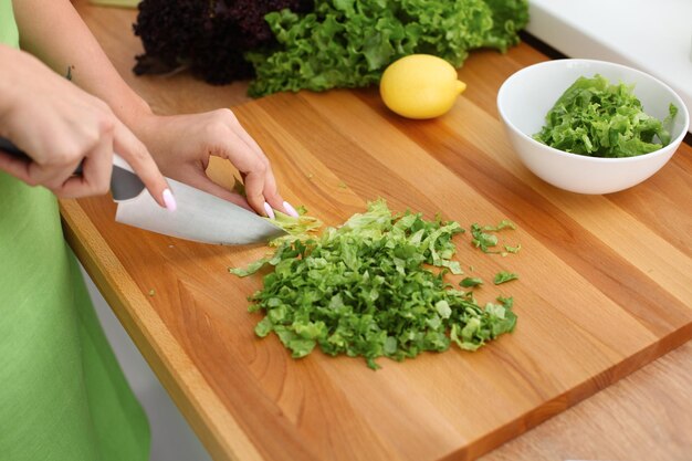 Gros plan sur des mains de femme cuisinant une salade de légumes dans la cuisine. Repas sain et concept végétarien.