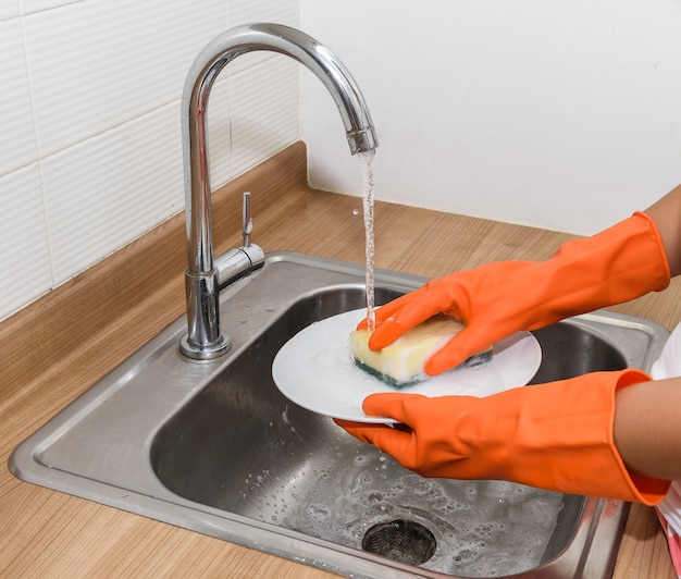 Gros plan des mains de femme faisant la vaisselle dans la cuisine