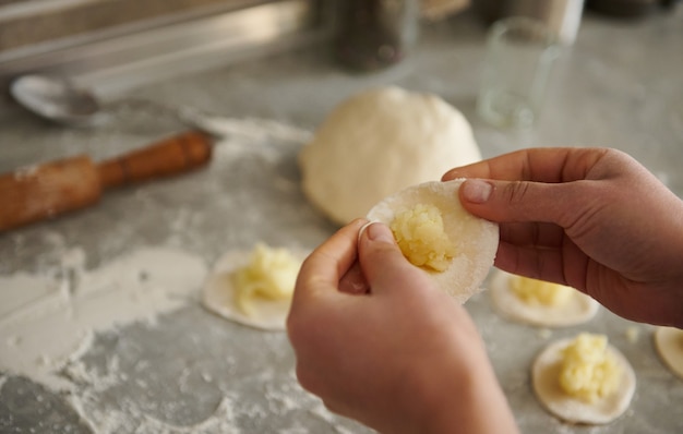 Gros Plan Des Mains De Femme Faisant Des Vareniki Traditionnels Ou Des Raviolis. Préparer Des Boulettes