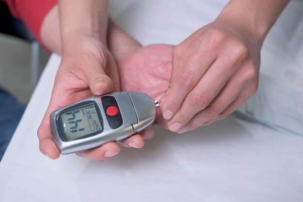 Gros plan sur les mains d'une femme médecin latine faisant un test pour mesurer les niveaux de sucre chez l'homme d'âge moyen