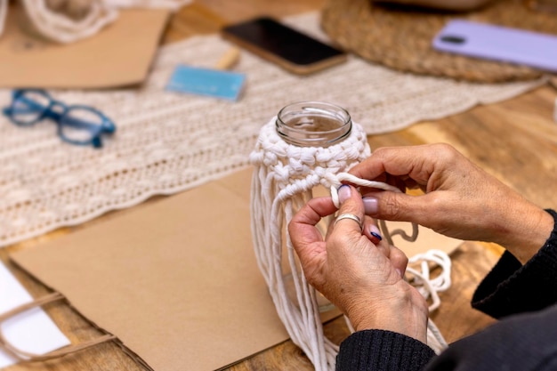 Gros plan des mains d'une femme plus âgée dans l'atelier de macramé fait main