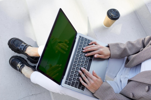 Gros plan des mains d'une femme qui travaille sur un ordinateur portable à l'extérieur Freelance et bureau n'importe où Écran vert maquette