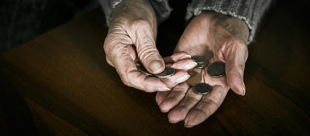 Gros plan sur des mains de femme senior avec des pièces en euros. Pensionné comptant de l'argent dans ses mains