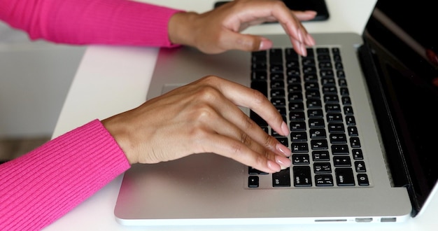 Gros plan des mains de femme tapant sur le clavier de l'ordinateur portable.
