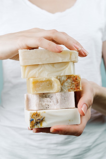 Photo gros plan des mains de femme tenant une pile de savon artisanal naturel, selective focus