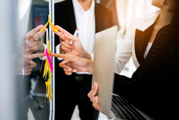 Gros plan des mains de femmes d'affaires asiatiques Réunion de remue-méninges avec des notes de papier collantes colorées sur le mur de verre pour de nouvelles idées Utilisation d'une méthodologie agile pour les entreprises dans un bureau de démarrage technologique