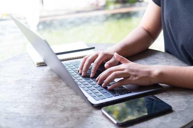 Photo gros plan sur les mains des femmes d'une entreprise indépendante à l'aide d'un ordinateur portable au café travail en ligne