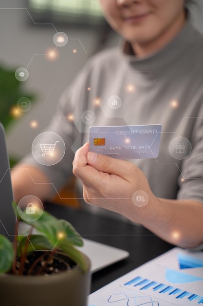 Gros plan des mains de femmes tenant un message de saisie de carte de crédit sur un ordinateur portable pour faire des achats en ligne avec des icônes de technologie