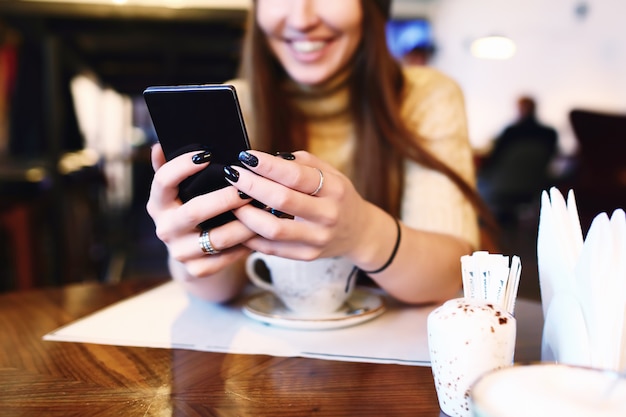 Gros plan des mains de femmes tenant un téléphone cellulaire