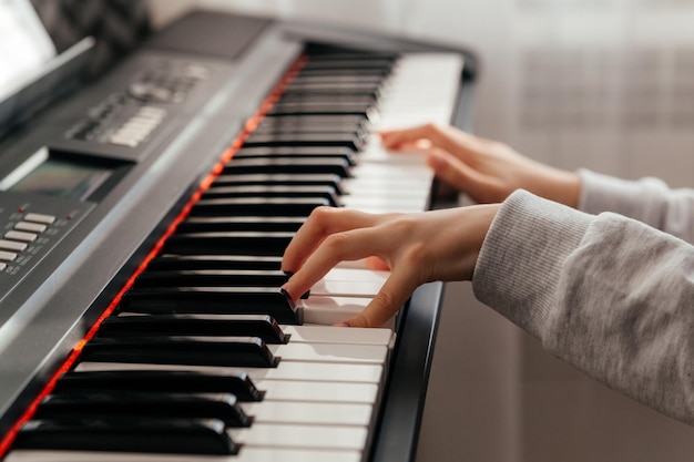 Gros plan des mains d'une fille caucasienne jouant du synthétiseur