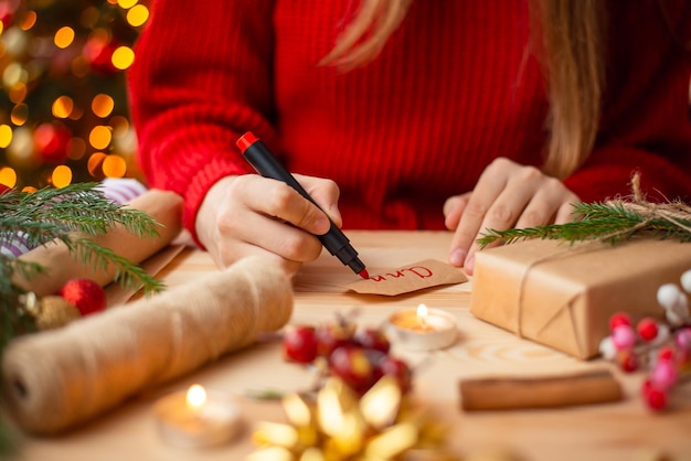 Gros plan des mains d'une fille signant un cadeau de Noël