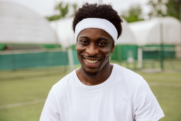 Gros plan des mains d'un gars à l'air africain regardant la caméra et souriant au tennis