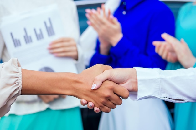 Gros plan sur les mains d'un groupe de cinq femmes de bureau musulmanes caucasiennes discutant avec une femme d'affaires partenaire châle et turban sur la tête peau parfaite et maquillage se serrant la main travail d'équipe et une idée d'affaire réussie