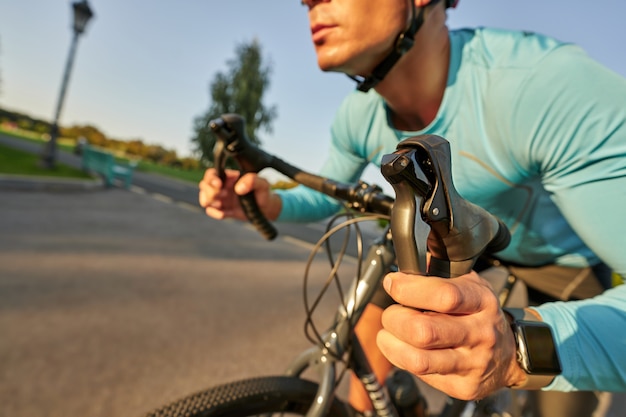gros plan des mains sur le guidon d'un cycliste professionnel chevauchant son vélo de route dans le parc.