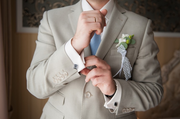 Gros plan des mains de l'homme avec anneau, cravate et bouton de manchette.