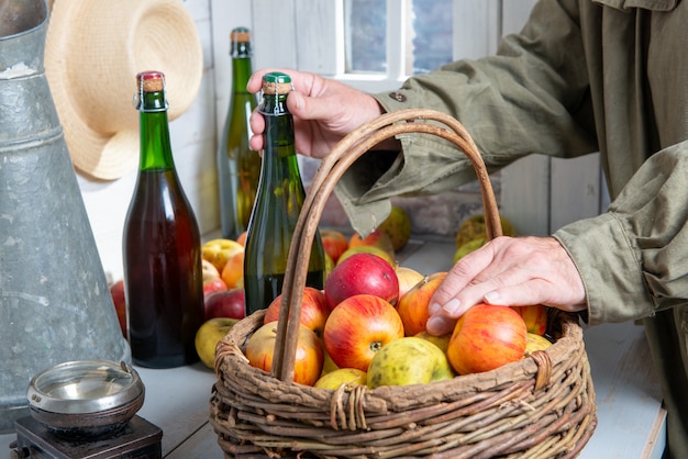 Gros plan des mains de l'homme avec une bouteille de cidre et de pommes