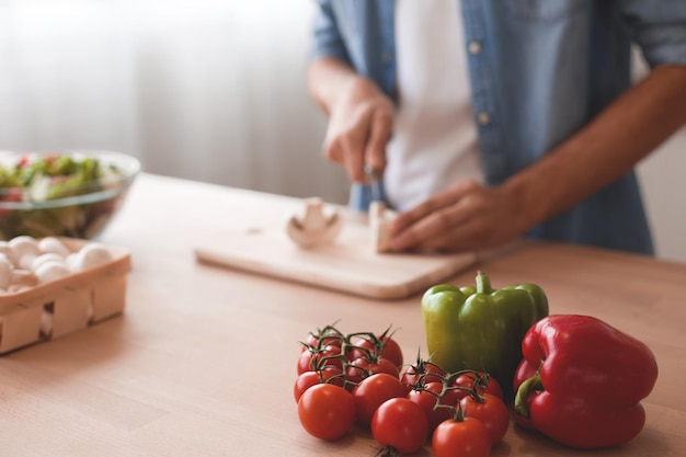 Gros plan sur des mains d'homme coupant des champignons pour la salade