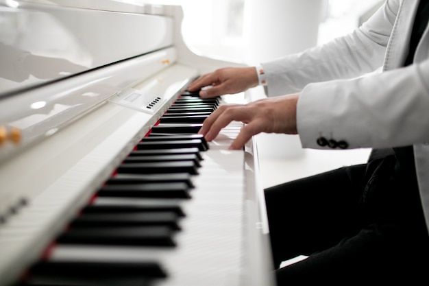 Photo gros plan des mains de l'homme du piano jouant les mains du pianiste masculin sur le clavier du piano à queue