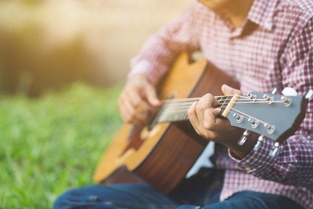 Gros plan des mains de l'homme jouant à la guitare acoustique