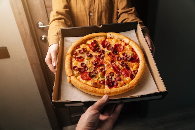Gros plan des mains de l'homme passent la commande de pizza au pepperoni