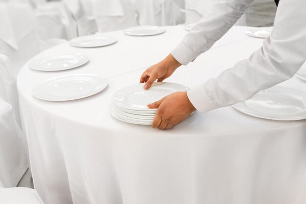 Gros plan des mains de l'homme serveur servant une table de banquet blanche au restaurant