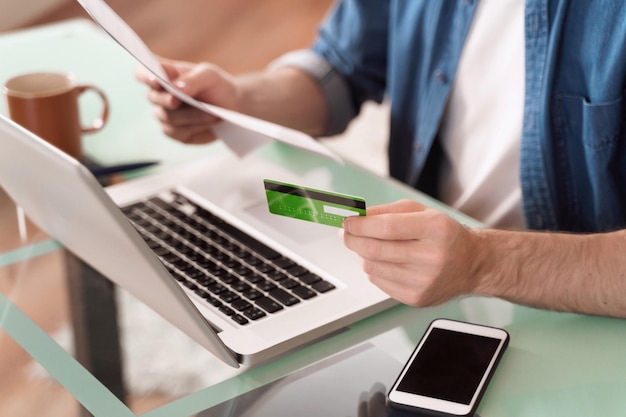 Photo gros plan des mains de l'homme utilisant une carte de crédit et un ordinateur portable pour le commerce électronique