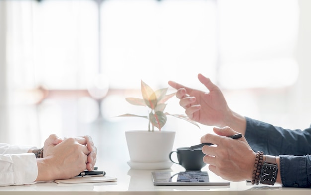 Gros plan sur des mains d'hommes faisant des gestes ou présentant tout en étant assis au bureau.