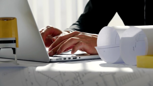 Gros plan sur des mains de jeune architecte tapant sur un clavier d'ordinateur portable en blanc