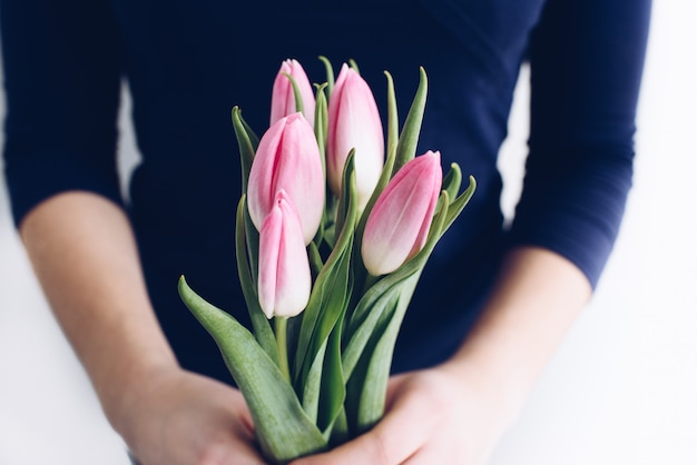 Gros plan des mains de jeune femme de race blanche tenant un bouquet de tulipes au printemps.