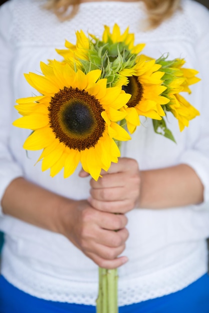 Gros plan des mains d'une jeune femme tenant de grands beaux tournesols Concept de vacances