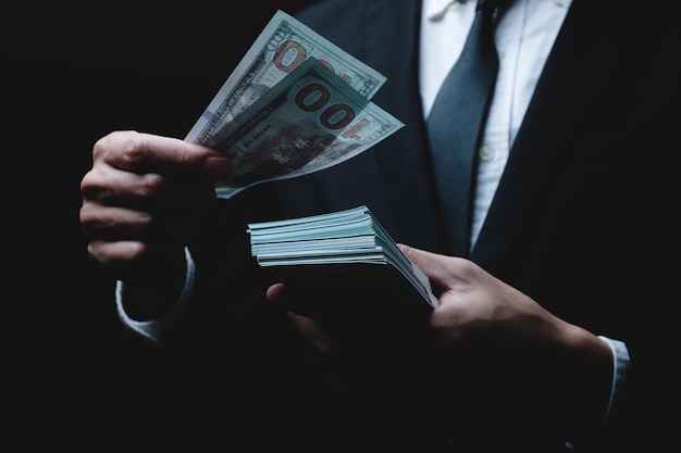 Gros plan des mains d'un jeune homme d'affaires et entrepreneur portant des vêtements formels en costume-cravate tenant et comptant de l'argent en papier