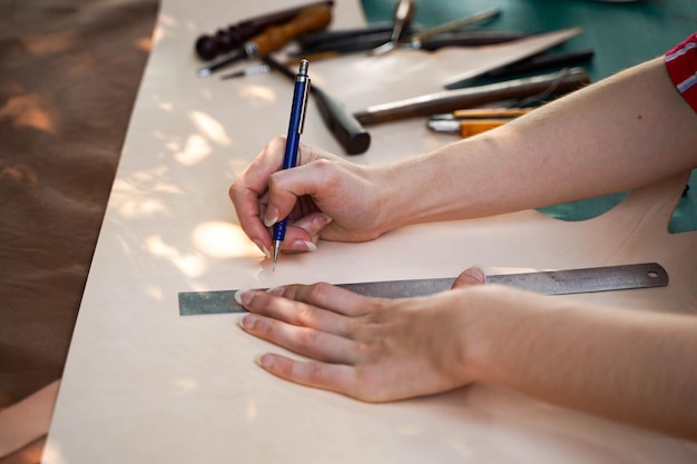 Gros plan des mains d'une jeune maroquinerie féminine dessine un dessin sur du cuir