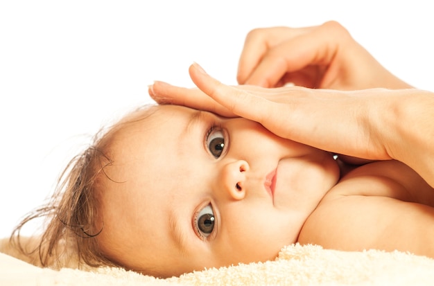 Gros plan des mains d'une jeune mère attentionnée se brosse les oreilles d'une jolie petite fille de six mois