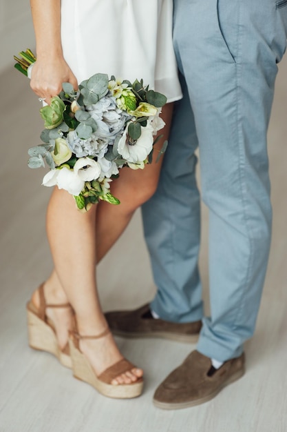 Gros plan des mains des jeunes mariés avec bouquet de mariage