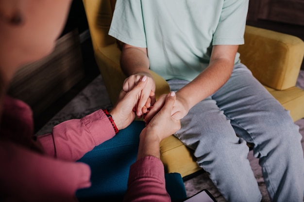 Gros plan des mains jointes d'une femme et des mains d'un enfant