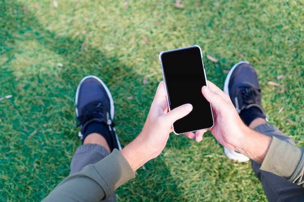 Gros plan des mains mâles tient un téléphone cellulaire à l'extérieur dans la rue. Homme utilisant un smartphone mobile.