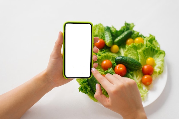 Gros plan des mains avec une maquette du téléphone avec le calcul des calories des aliments cuits