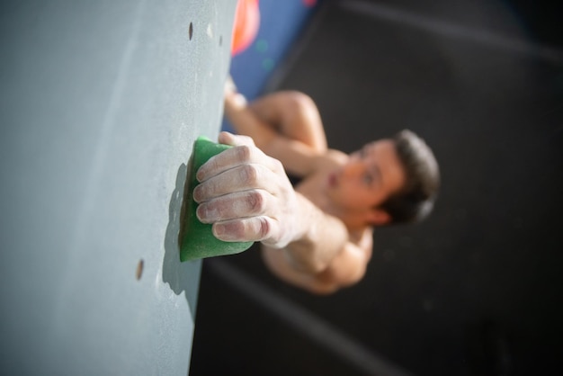 Gros plan des mains masculines avec de la poudre de talc sur le mur de bloc. Homme flou grimpant. Sport, passe-temps, concept de bien-être