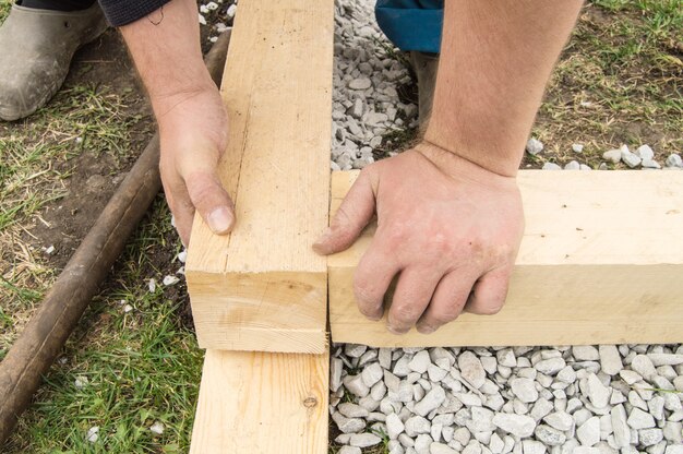 Gros plan sur des mains masculines rugueuses utilisant du nouveau bois pour le travail, à l'extérieur.