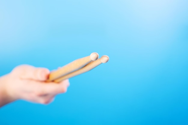 Gros plan des mains masculines tenant des baguettes sur un fond bleu de cours de batterie en ligne